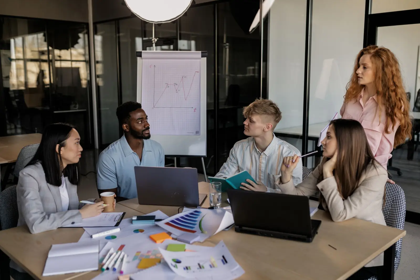 A marketing team around a meeting table with laptops and notes
