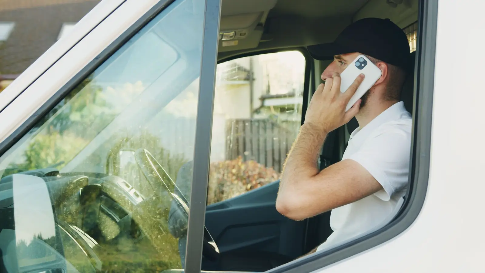 A tradesperson taking a phone call in the driver's seat of a van