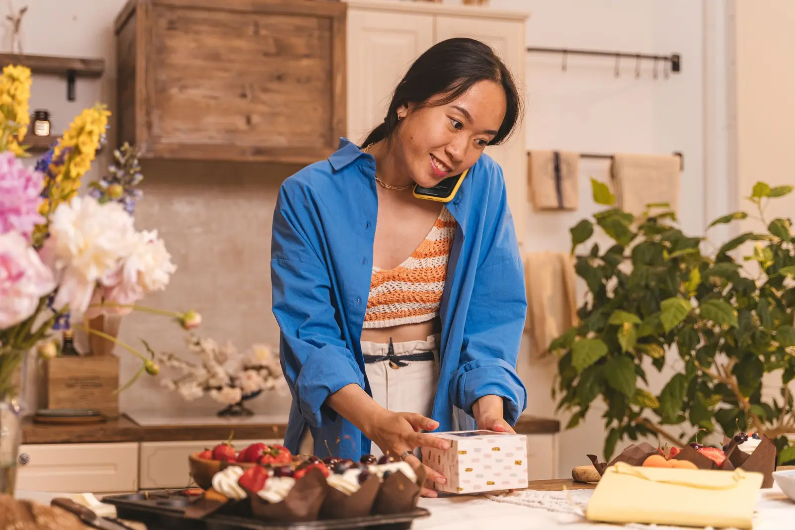 Une personne au téléphone derrière un comptoir de gâteaux et de fleurs